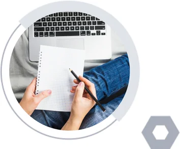 Researcher drafting notes beside a laptop